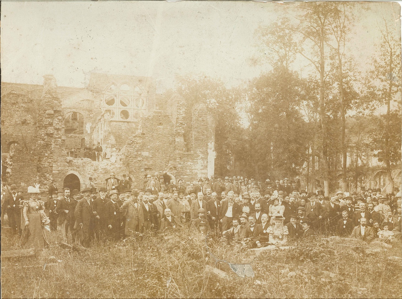Foto van Dr. P.J.H. Cuypers met gezamenlijk personeel van de Cuypers' Kunstwerkplaatsen bij een bezoek aan een ruïne.