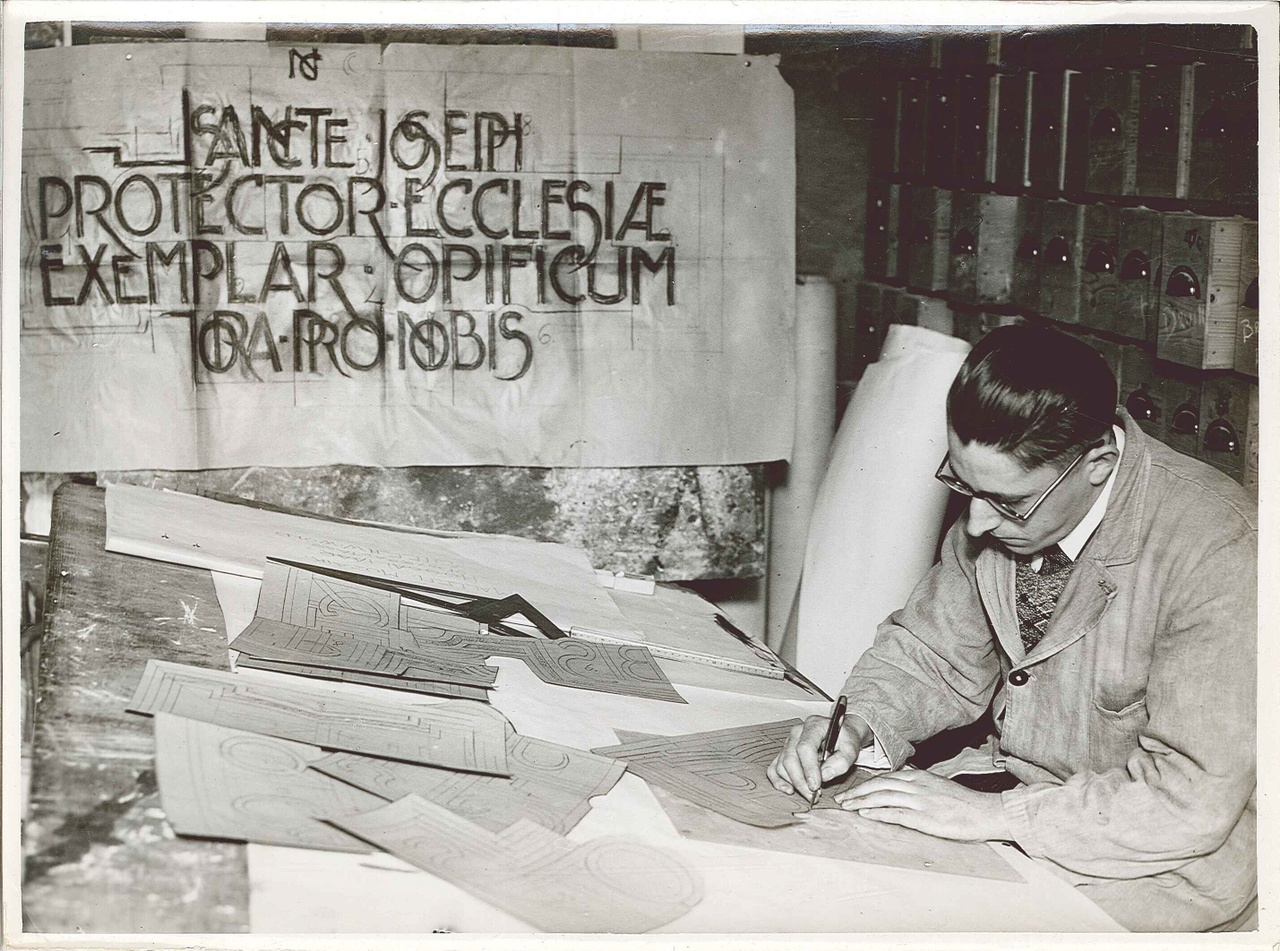 Foto uit de Cuypers' Kunstwerkplaatsen van rond 1930: Dhr. Jean Tunderman bezig met het snijden van spiegelbeeldsjablonen.