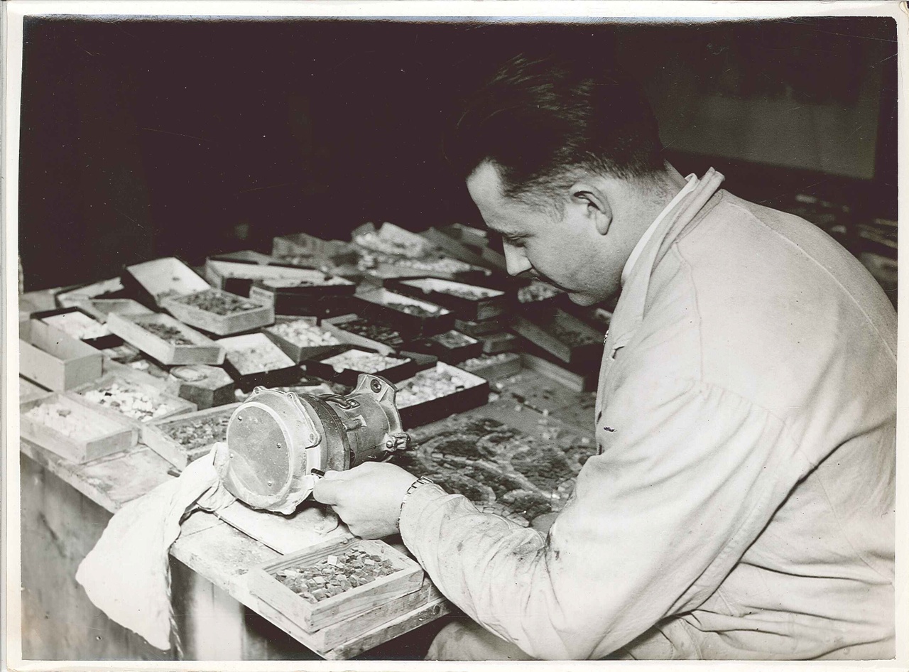 Foto uit de Cuypers' Kunstwerkplaatsen van rond 1930: Dhr. Piet Peeters bezig met het slijpen van mozaïeksteentjes.