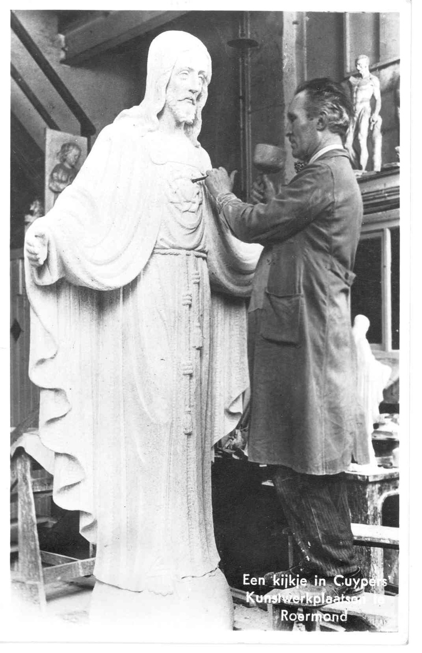 Foto van een man met hamer en beitel werkend aan een H. Hartbeeld in Cuypers kunstwerkplaatsen..