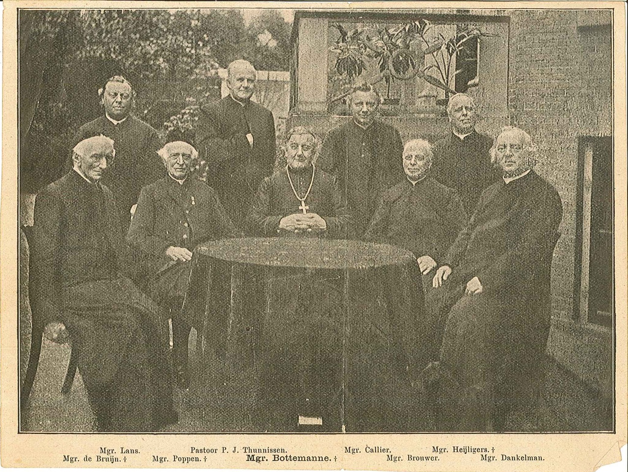 Krantenknipsel met daarop een foto met negen priesters waarvan acht monseigneurs en een pastoor