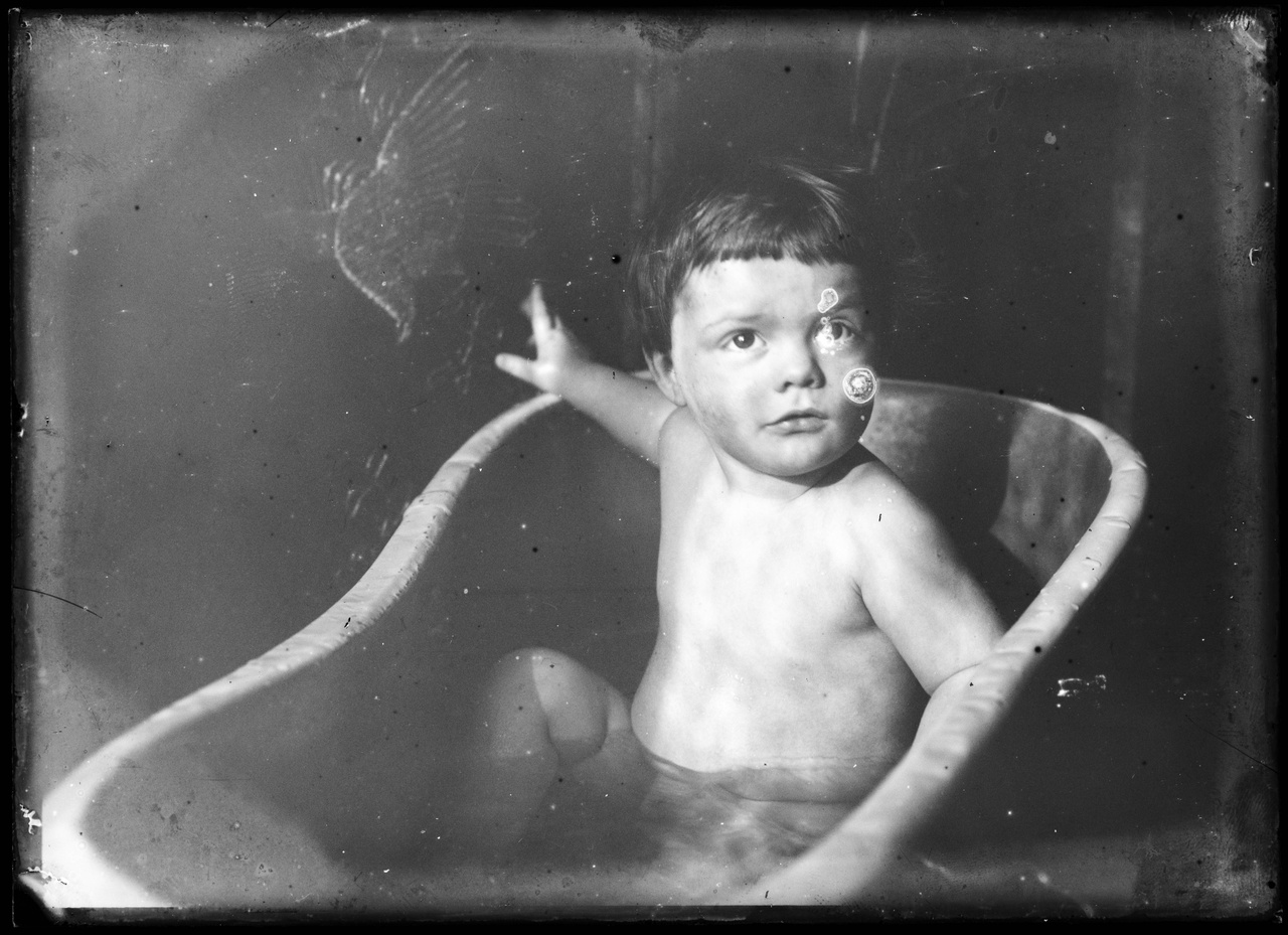 Glasnegatief van een foto van van een kind (Charles Cuypers) in bad