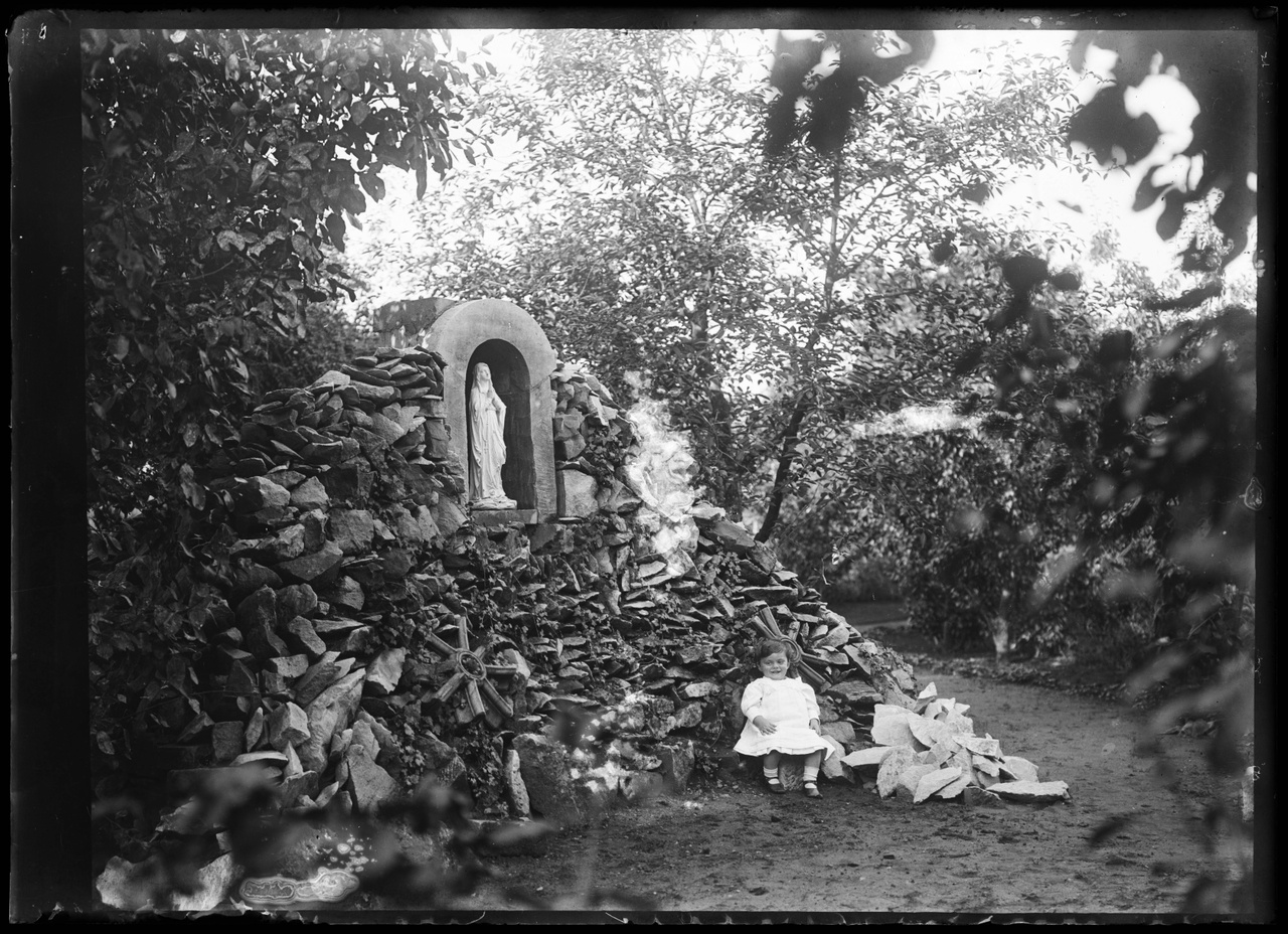 Glasnegatief van foto van kind in tuin met Lourdesgrot