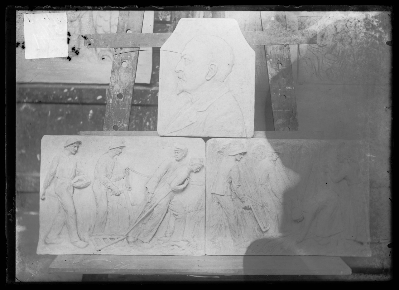 Glasnegatief van foto van producten uit de Cuypers' Kunstwerkplaatsen uit kist met nummer 37: "Drie panelen: een borstbeeld, boer met ploeg en boer aan het maaien".