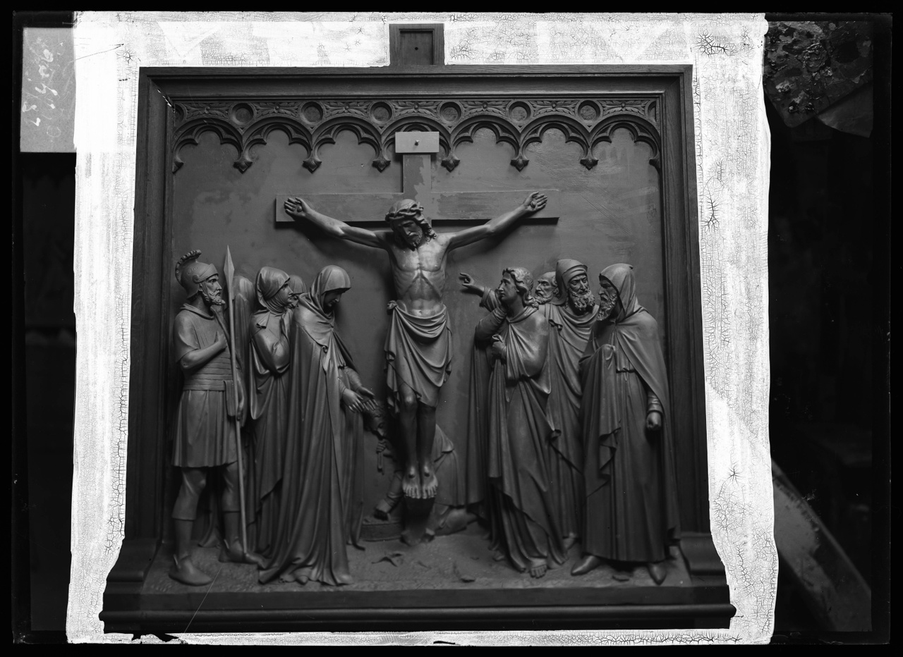 Glasnegatief van foto van producten uit de Cuypers' Kunstwerkplaatsen: "Foto van een houten sierlijst met daarin een reliëf van een kruiswegstatie: Jezus hangt aan het kruis".