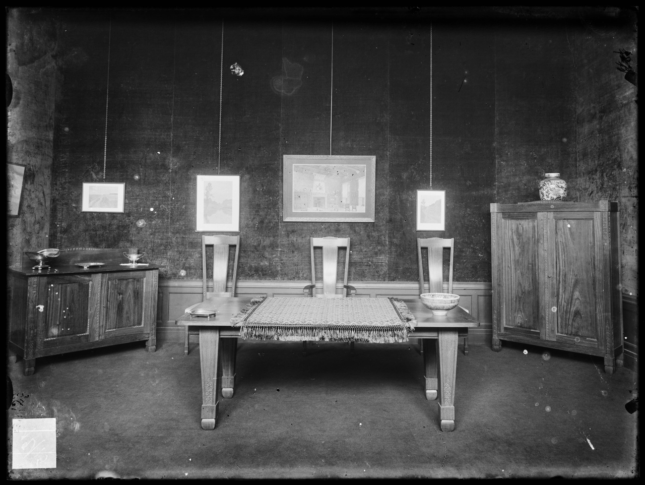 Glasnegatief van foto van producten uit de Cuypers' Kunstwerkplaatsen: "Foto van een interieur met een lage tafel, twee kasten en drie stoelen".