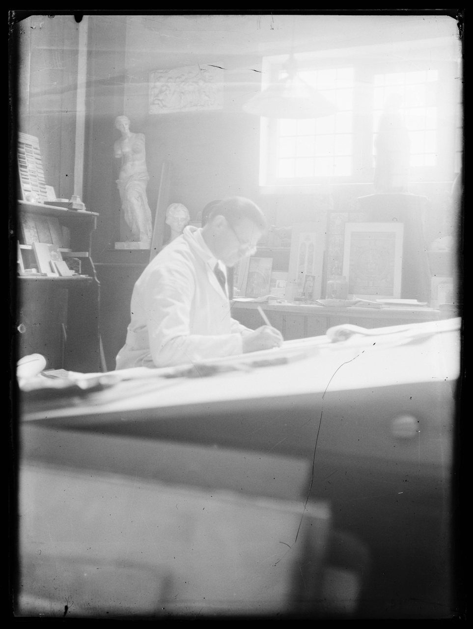 Glasnegatief van foto van producten uit de Cuypers' Kunstwerkplaatsen: "Foto van een werknemer aan de tekentafel".