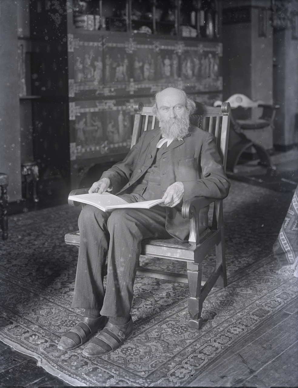 Glasnegatief van een foto van Pierre Cupyers met een boek in een fauteuil