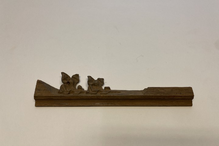 Houten balkje met twee bladmotiefjes.