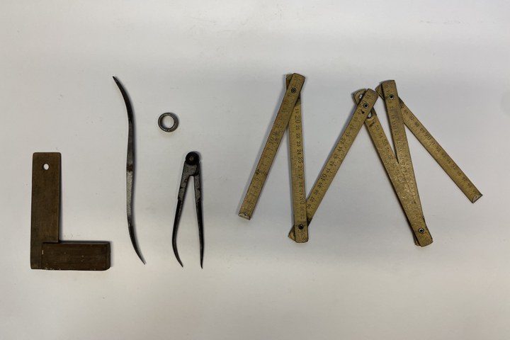 Houten rechthoek, aan twee kanten gebogen rasp, passer, metalen ringetje en een duimstok